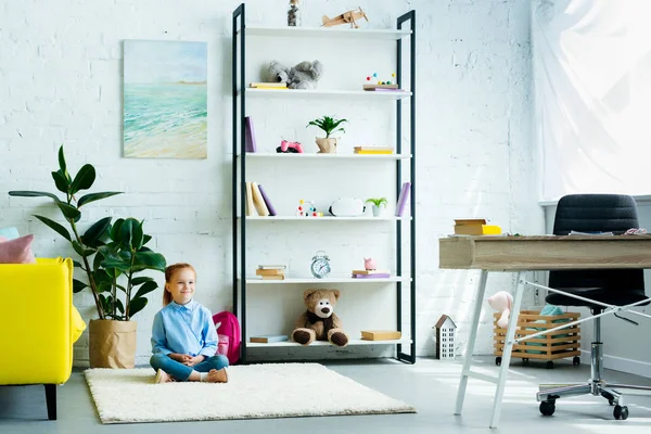 Adorabile bambino sorridente seduto su tappeto a casa — Foto stock