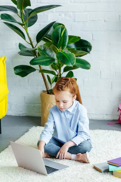 Vista ad alto angolo di bella studentessa rossa che studia con computer portatile e libri a casa — Foto stock