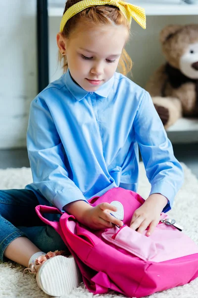 Entzückendes Kind packt rosa Schultasche zu Hause ein — Stockfoto