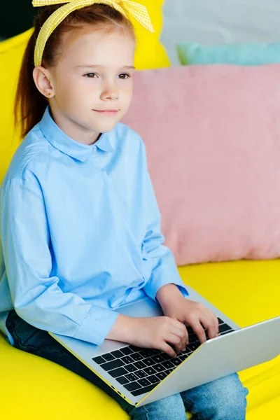 Adorable pequeño pelirrojo niño sentado y usando el ordenador portátil - foto de stock