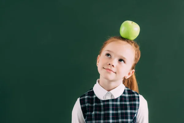 Pensieroso poco dai capelli rossi studentessa con mela sulla testa guardando altrove — Foto stock