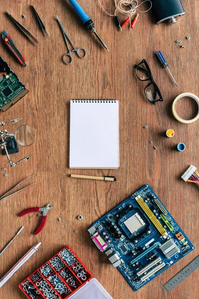 Vista superior del libro de texto vacío y la pluma con herramientas de reparación y placa base en la mesa de madera - foto de stock