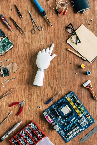 Vue du haut du bras prothétique pointant du doigt sur la table avec des outils — Photo de stock