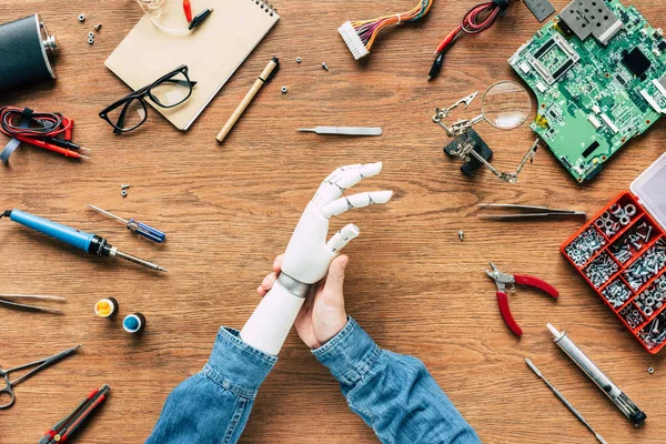 Imagem cortada do homem com amputado adiando braço protético na mesa com instrumentos — Fotografia de Stock