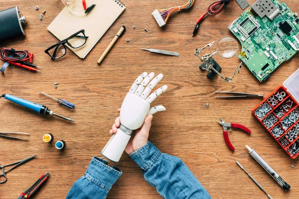 Cropped image of man with amputee putting on robotic hand on table with tools — Stock Photo