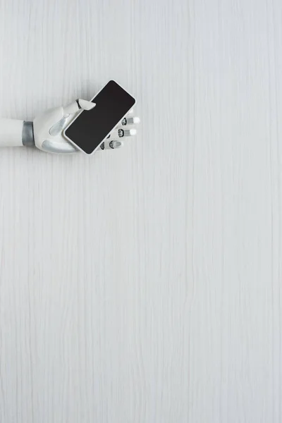 Vista parcial del brazo protésico que sostiene el teléfono inteligente con pantalla en blanco - foto de stock