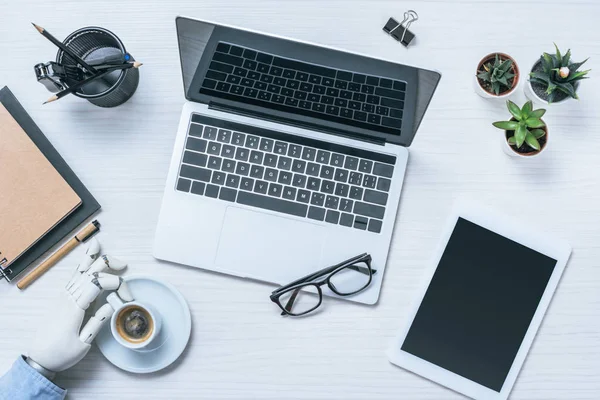 Imagem cortada de homem de negócios com prótese braço descansando e beber café à mesa com laptop no escritório — Fotografia de Stock