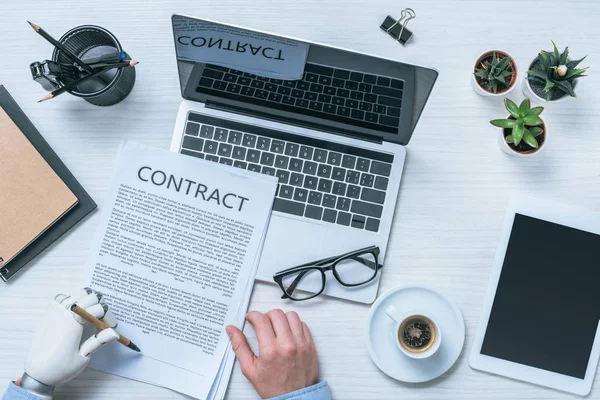 Cropped image of businessman with prosthetic arm signing contract at table — Stock Photo