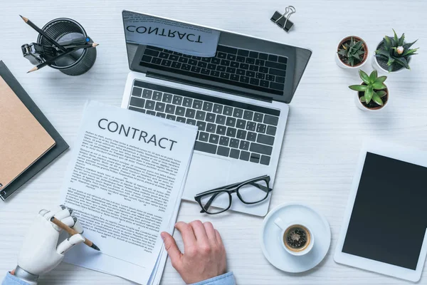 Imagen recortada de hombre de negocios con contrato de firma de brazo protésico en la mesa - foto de stock