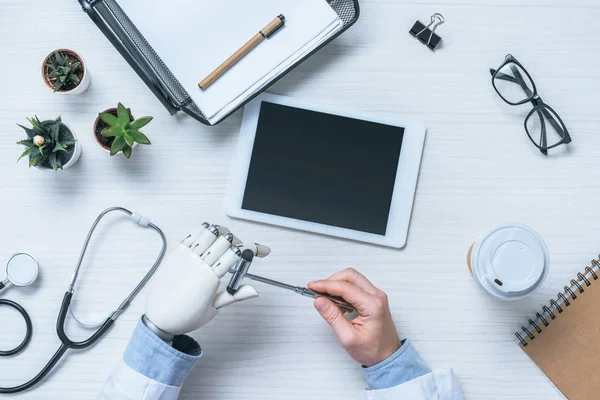 Imagen recortada de neurólogo masculino con brazo protésico sentado a la mesa con martillo reflejo — Stock Photo