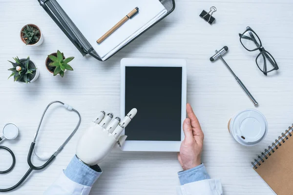 Partial view of male doctor with prosthetic arm using digital tablet with blank screen — Stock Photo