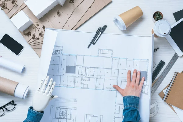 Vue partielle de l'architecte masculin avec bras prothétique regardant le plan directeur — Photo de stock