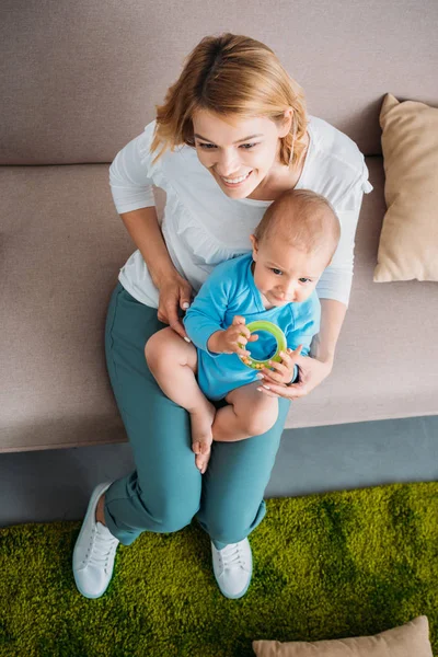 High angle view of mother holding her adorable child on knees while sitting on couch — Stock Photo