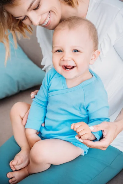 Primer plano retrato de la risa niño pequeño sentado en las rodillas de la madre - foto de stock