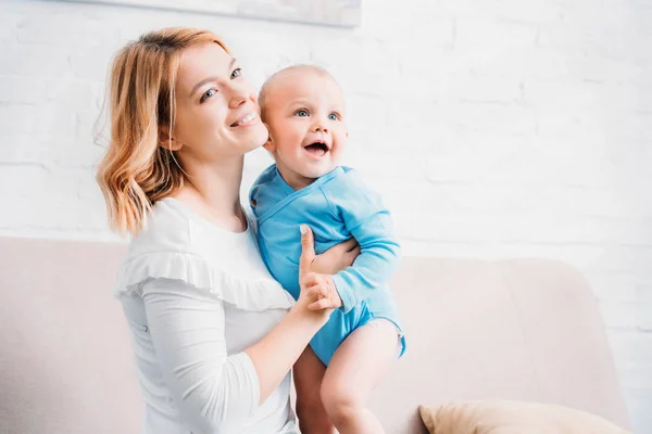 Madre sorridente che abbraccia il bambino felice a casa — Foto stock