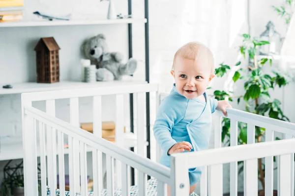 Happy little baby standing in crib at home — Stock Photo