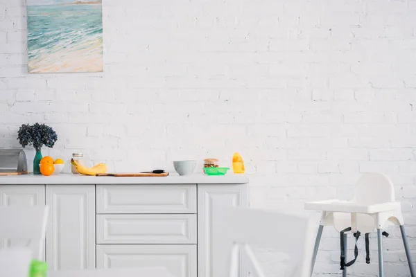 Интерьер современной светлой кухни с фруктами на столе и стульчик — стоковое фото