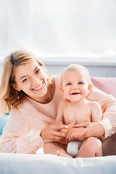 Happy mother and child relaxing on bed at home and looking at camera — Stock Photo