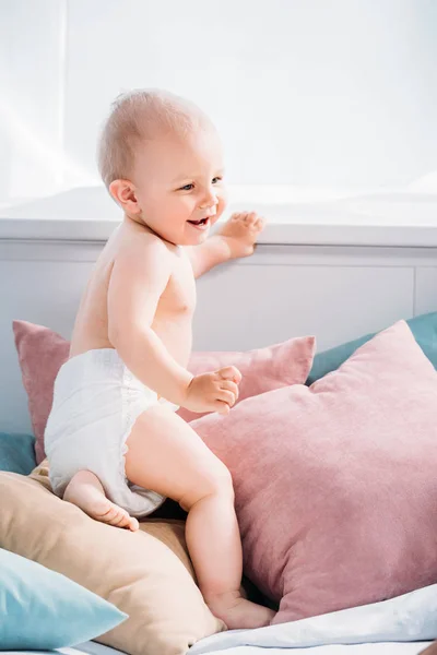 Happy little baby on bed with lot of pillows — Stock Photo