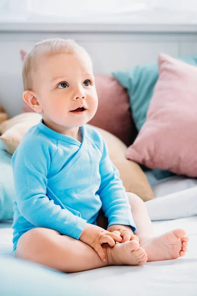 Entzückendes kleines Baby sitzt im Bett und schaut auf — Stockfoto