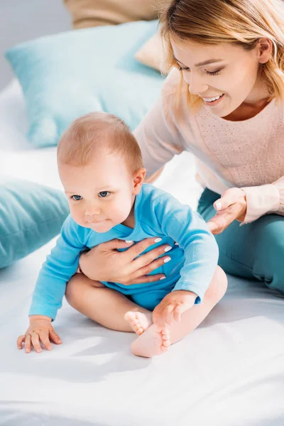 Primo piano colpo di madre felice e bambino seduto sul letto a casa — Foto stock