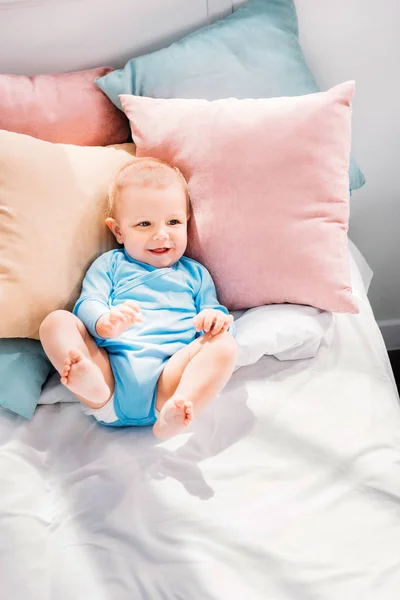 Vista de ángulo alto de la risa pequeño bebé acostado en la cama — Stock Photo