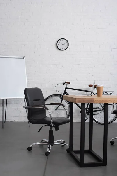 Laptop and coffee to go on table in modern office — Stock Photo