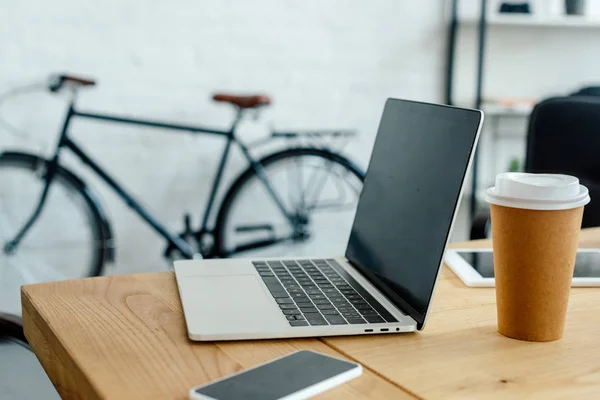 Close-up view of laptop and smartphone on table in office — Stock Photo