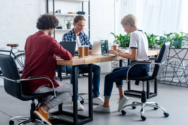 Young start up team using laptops while sitting together at workplace — Stock Photo