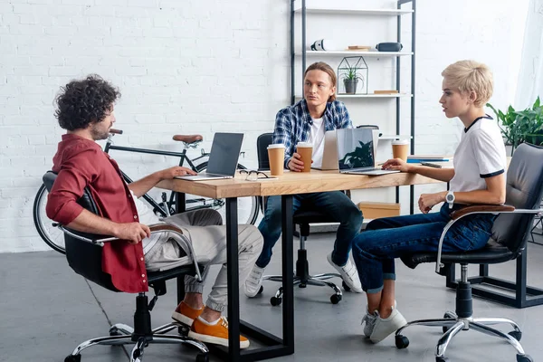 Jeune équipe de démarrage utilisant des appareils numériques sur le lieu de travail — Photo de stock