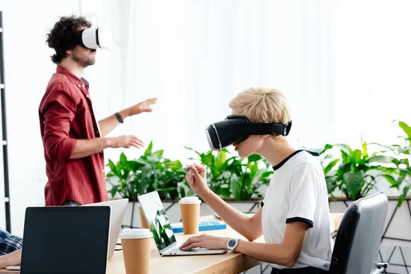 Молодые сотрудники в гарнитурах виртуальной реальности, работающие в офисе — стоковое фото