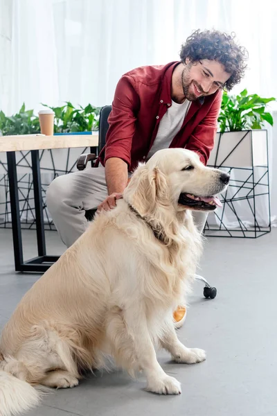 Smiling young man stroking dog at workplace — Stock Photo