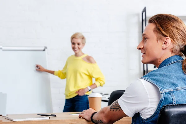 Un jeune homme et une jeune femme souriants qui travaillent ensemble au bureau — Photo de stock