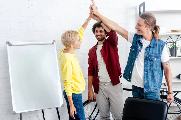 Junges Start-up-Team gibt High Five bei gemeinsamer Arbeit am Whiteboard — Stockfoto