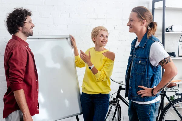 Smiling young business colleagues standing near whiteboard and discussing new project — Stock Photo