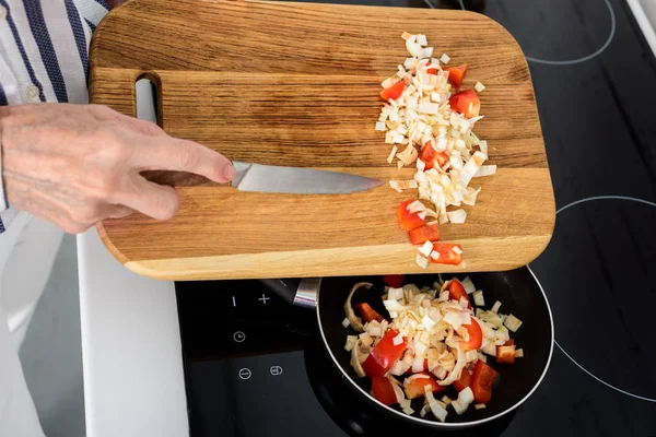 Image recadrée de la femme âgée mettant des légumes sur la poêle dans la cuisine — Photo de stock