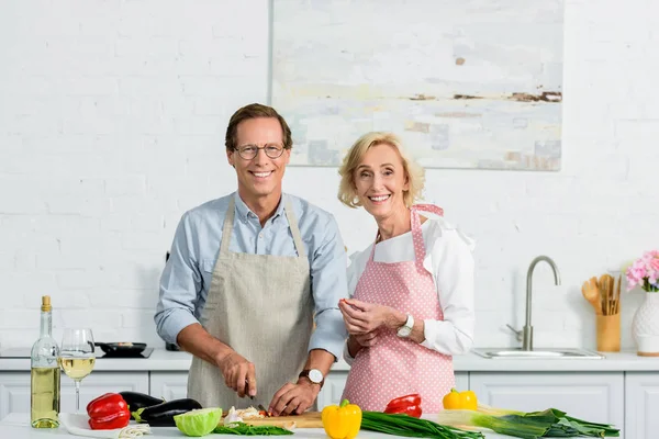 Pareja de ancianos cocinar en la cocina y mirando a la cámara - foto de stock