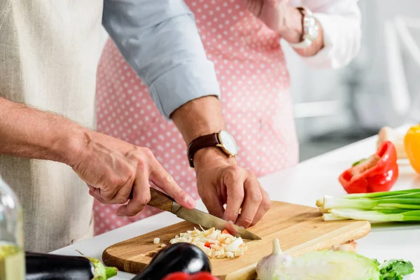 Abgeschnittenes Bild eines älteren Mannes, der in der Küche Gemüse auf Holzbrettern schneidet — Stockfoto