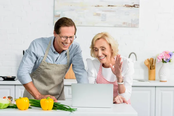 Senior couple having video call and using laptop at kitchen — Stock Photo