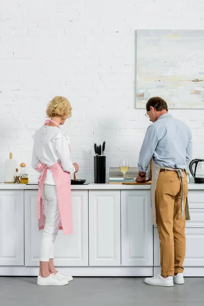 Blick von hinten auf Seniorenpaar, das gemeinsam in Küche kocht — Stockfoto
