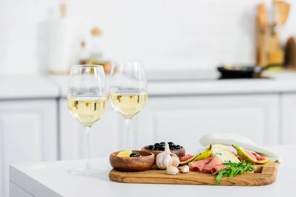 Delicious snacks on wooden board and glasses of wine on table — Stock Photo