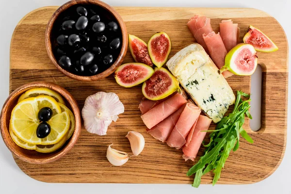 Top view of delicious snacks on wooden board on table — Stock Photo