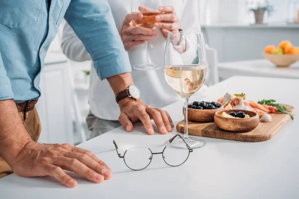 Foto recortada de pareja mayor bebiendo vino y comiendo deliciosos bocadillos en casa - foto de stock