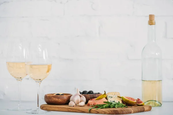 Крупный план бокалов и бутылки вина и вкусные закуски на столе — стоковое фото