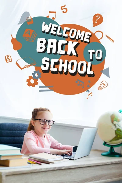 Adorable enfant en lunettes souriant à la caméra tout en étudiant avec ordinateur portable à la maison avec lettrage