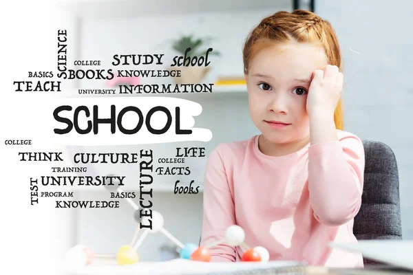 Beautiful red haired schoolgirl looking at camera while studying with molecular model at home, with school word — Stock Photo