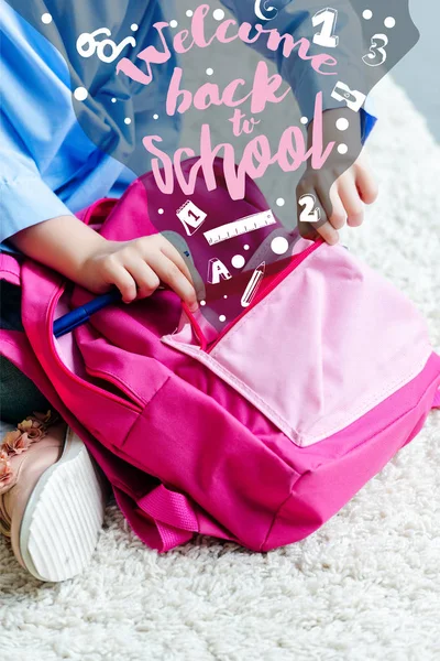 Recortado tiro de niño embalaje rosa bolsa de la escuela en casa, bienvenido de nuevo a la escuela - foto de stock