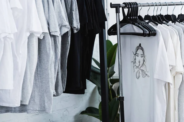 Foyer sélectif de t-shirts avec impression sur cintres dans le studio de conception de vêtements — Photo de stock