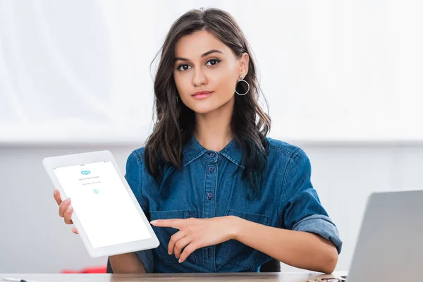 Attractive young woman pointing on digital tablet screen with skype application — Stock Photo