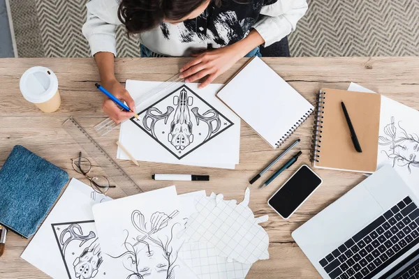 Overhead view of female artist painting at table with laptop and smartphone — Stock Photo